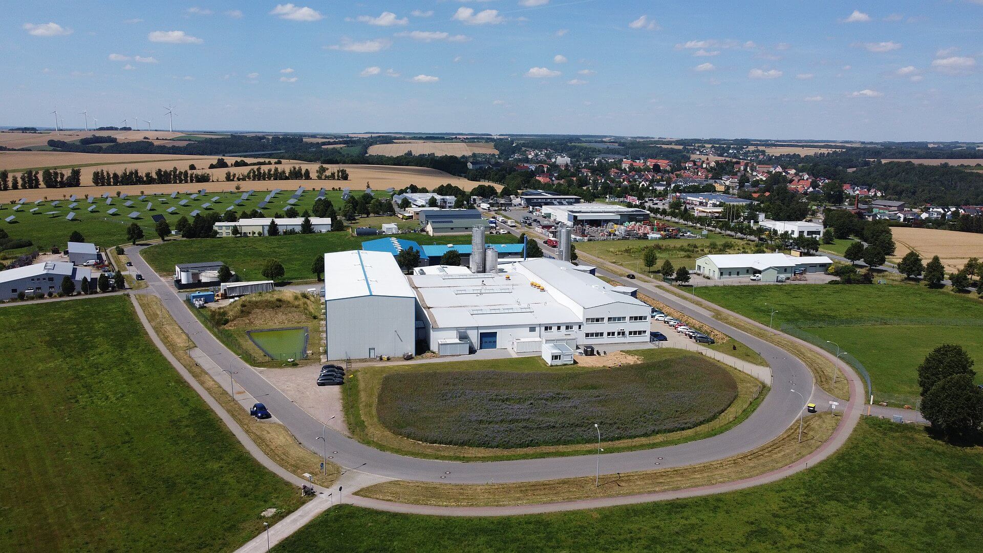 Eine Luftaufnahme des Gewerbegebiet Tauscha. Man sieht verschiedene Hallen, die Straße und Felder